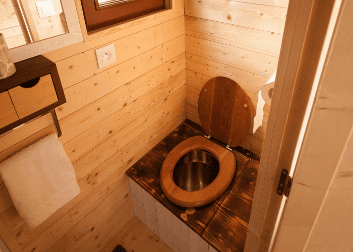 Toilettes sèches en bois installées dans une cabine intérieure, illustrant une solution d’assainissement écologique et économe en eau.