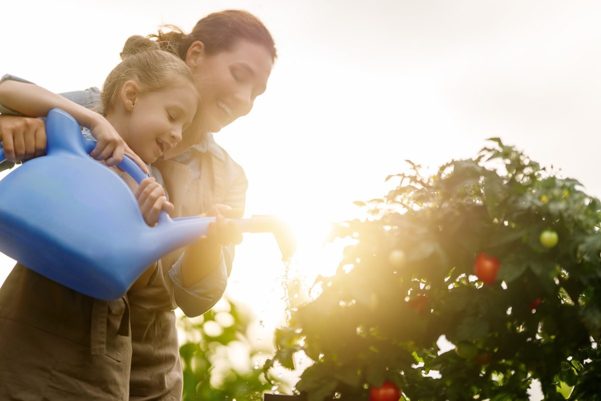 M&egrave;re et sa fille arrosant le potager avec de l'eau de pluie non potabilis&eacute;e, usage ext&eacute;rieur jardin