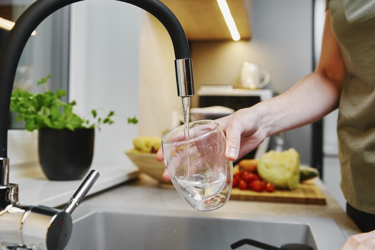Verre d'eau rempli au robinet de cuisine, eau de pluie filtr&eacute;e et trait&eacute;e pour un usage domestique potable